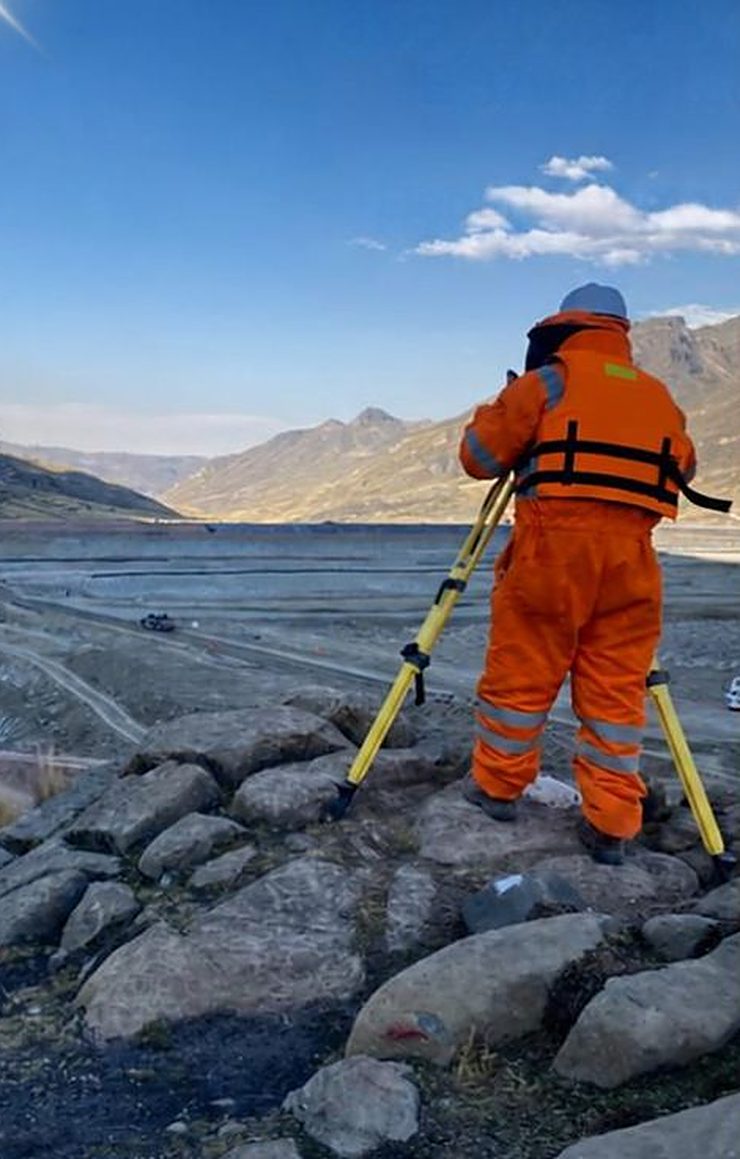 Topógrafo de Diamond con equipo de protección personal junto a una laguna andina